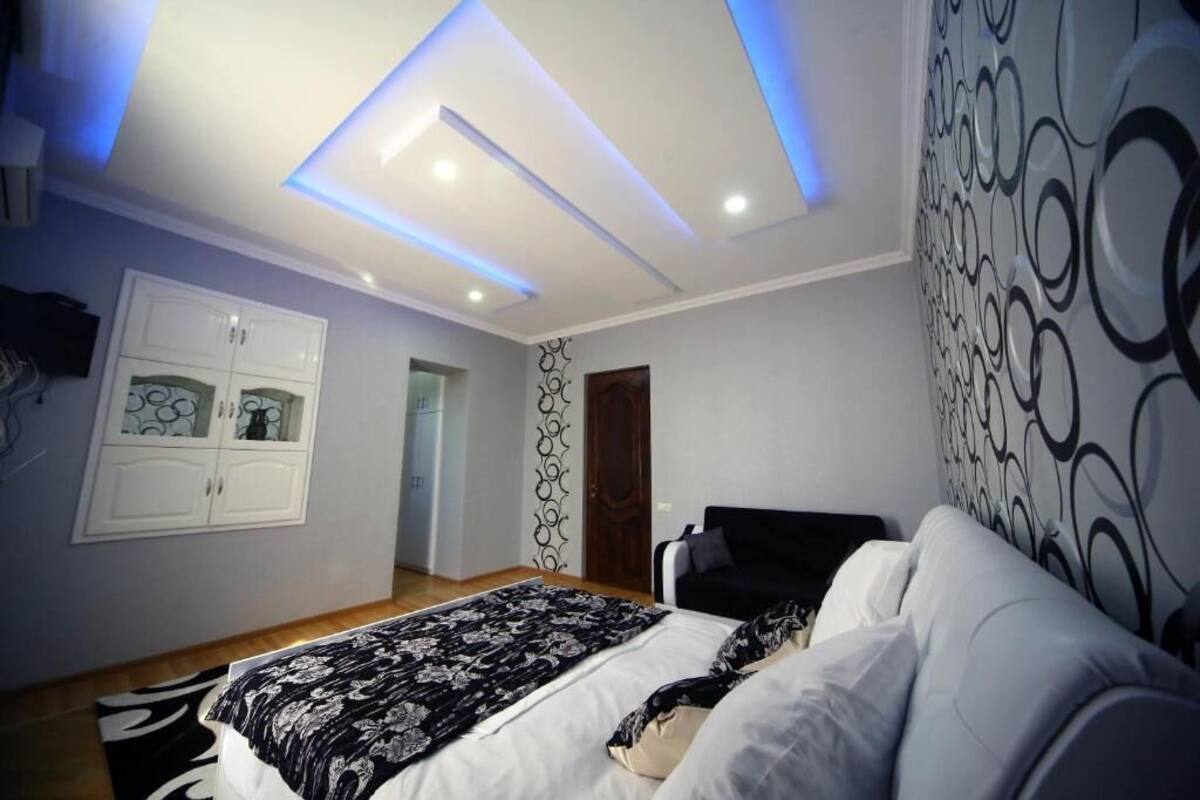Quarto com cama, guarda-roupa e teto com iluminação embutida.
