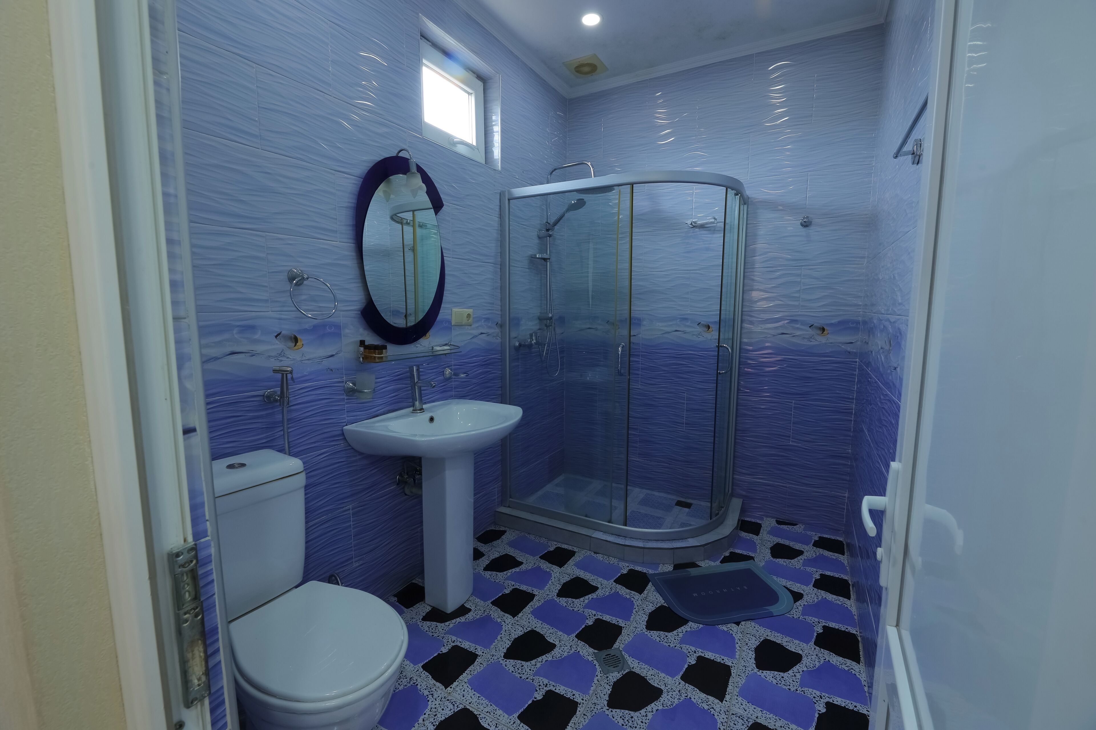 A bathroom with a toilet, sink, and glass shower enclosure.