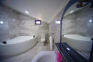 A modern bathroom with two large freestanding tubs, a toilet, and a mirror with a decorative frame.