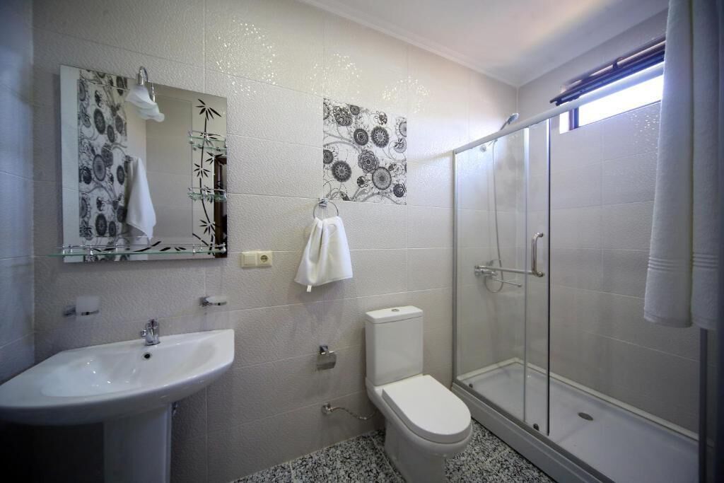 Un baño con lavamanos, inodoro y cabina de ducha de vidrio.