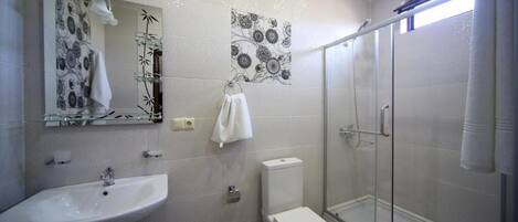 Un baño con lavamanos, inodoro y cabina de ducha de vidrio.
