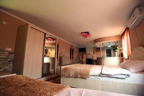 A hotel room with two beds, a desk, a mirror, and a TV.