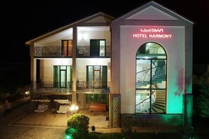 A two-story hotel with a balcony, outdoor seating, and a staircase leading to the entrance. - Hotel Harmony (Tsqaltubo)
