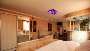 Une chambre d’hôtel comprenant un lit, un bureau, une chaise, une petite table et une salle de bain avec un miroir.