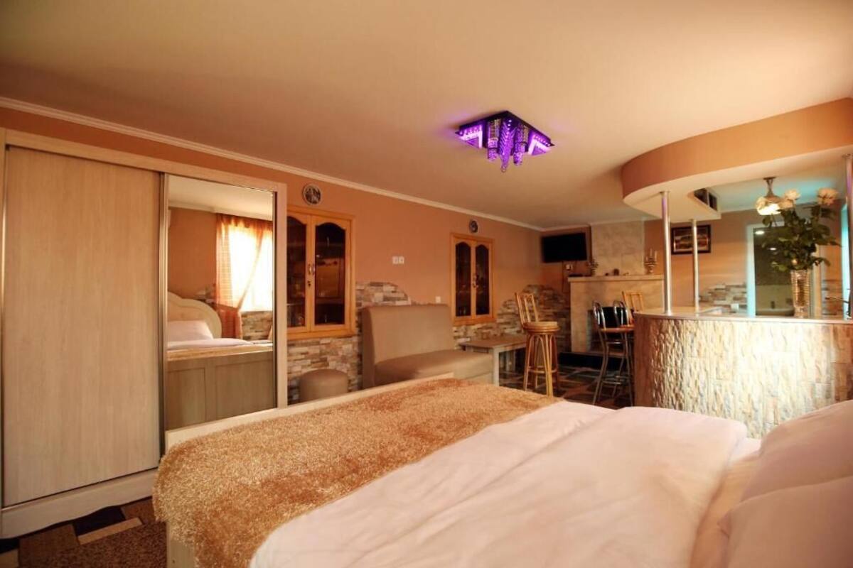 Quarto de hotel com uma cama, uma mesa de escritório, uma cadeira, uma mesinha e um banheiro com espelho.