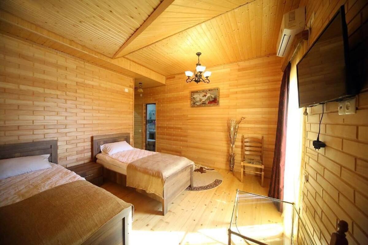 Quarto de cabana de madeira com duas camas, um candelabro, uma televisão e lareira.