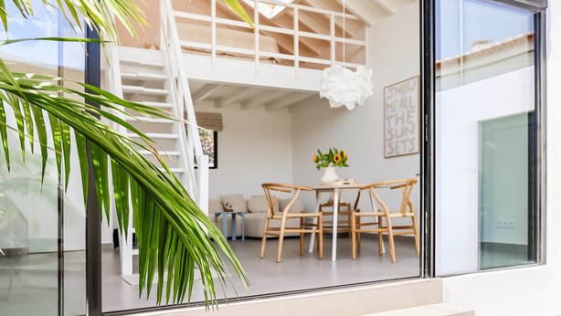 A modern interior with a glass wall, a wooden dining table, and a staircase leading to an upper level. - JOSY Atelier (Ferrel)