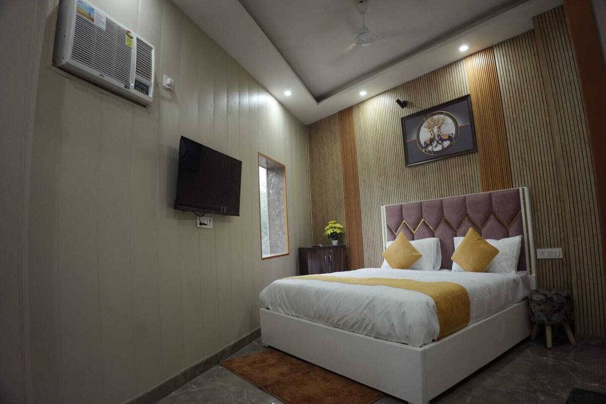 A modern hotel room with a large bed, a flat-screen TV mounted on the wall, and a ceiling fan.