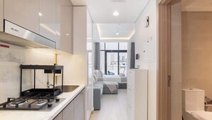 Una cocina moderna con estufa a gas, horno empotrado y microondas. Cuenta con un comedor con mesa y sillas, y vistas a la ciudad a través de amplios ventanales.