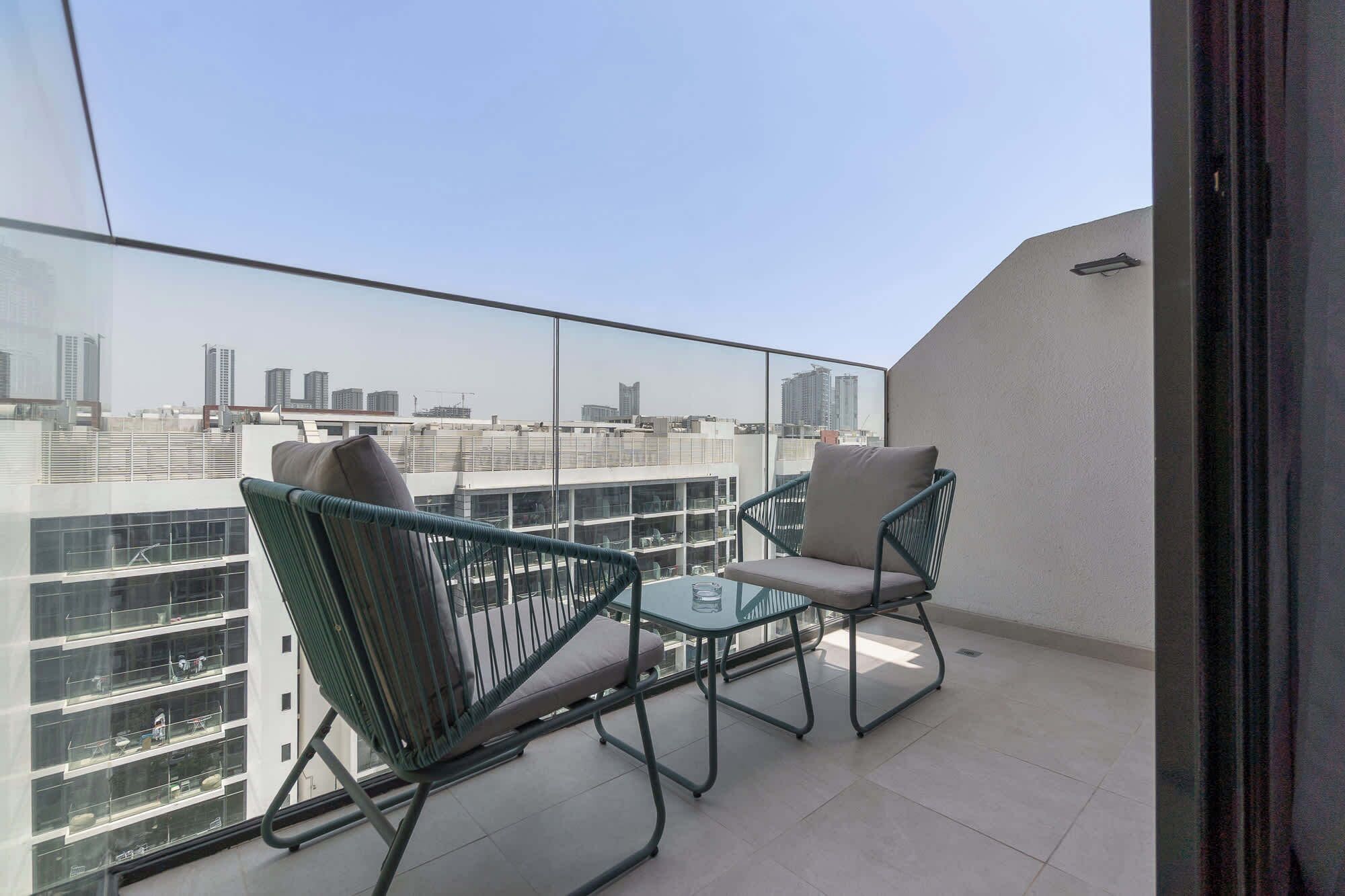 Varanda com duas cadeiras e uma pequena mesa, com vista para a cidade.