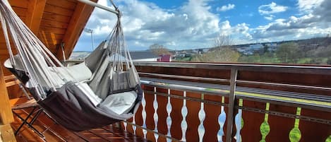 En hængekøjsstol på en balkon med udsigt over en by og bakker.