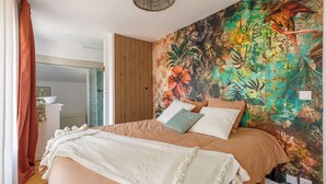 A bedroom with a large bed, a wooden slat wall, and a vibrant floral tapestry.