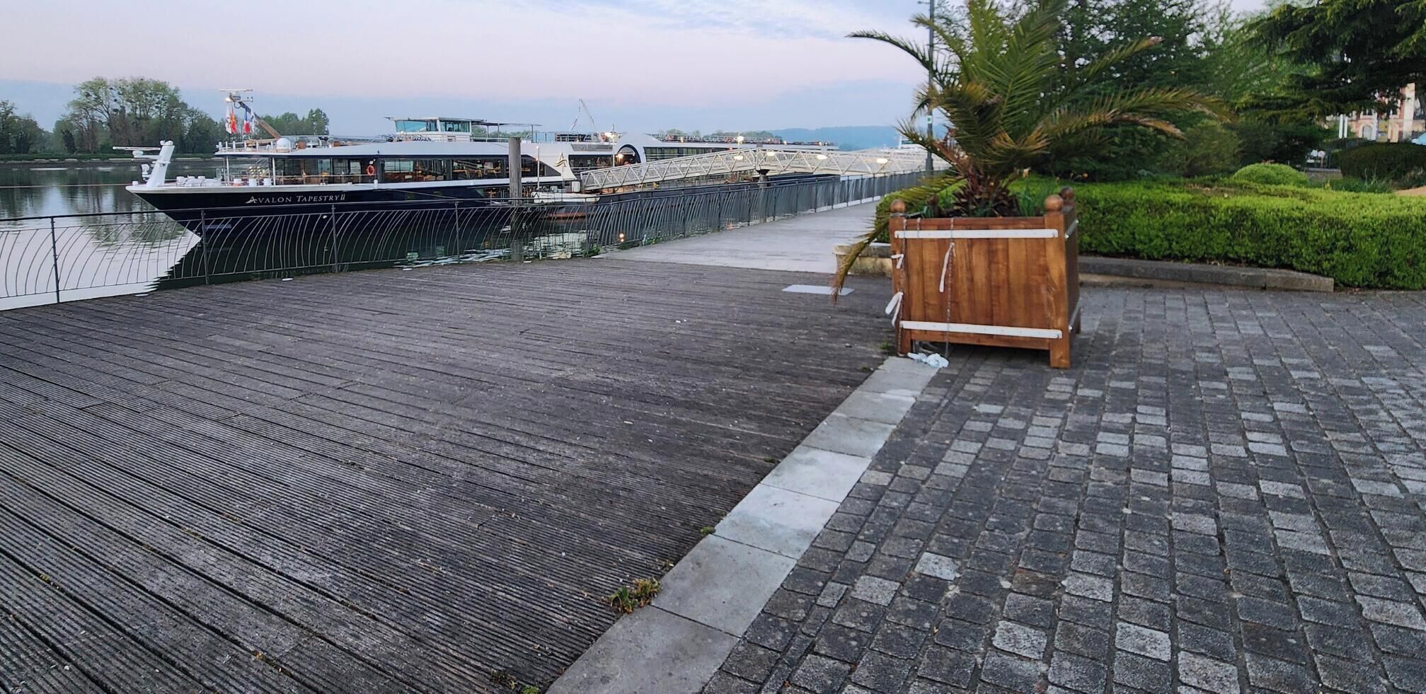 Un paseo marítimo de madera junto a un río, con un bote amarrado a la izquierda.