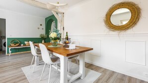 A dining area with a wooden table, white chairs, and a mirror on the wall.
