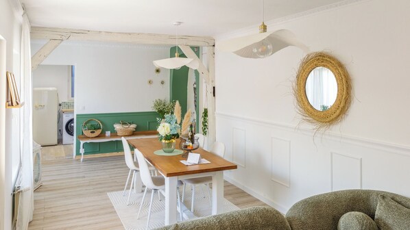Un comedor con una mesa de madera, sillas blancas y una pared de acento verde.