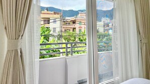 Een kamer met balkon, een schuifpui en gordijnen.
