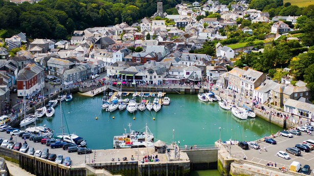 A coastal town with a marina filled with boats, surrounded by historic buildings and a church tower.