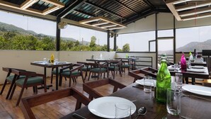 A restaurant with outdoor seating, tables, chairs, and a view of the mountains.