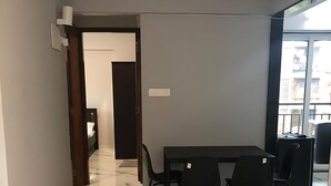 Ein moderner Raum mit Marmorboden, einem Esstisch mit Stühlen, einem großen Fenster und einer Tür zu einem anderen Raum.