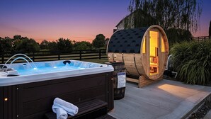 A hot tub and wooden barrel sauna with steps leading to the sauna.