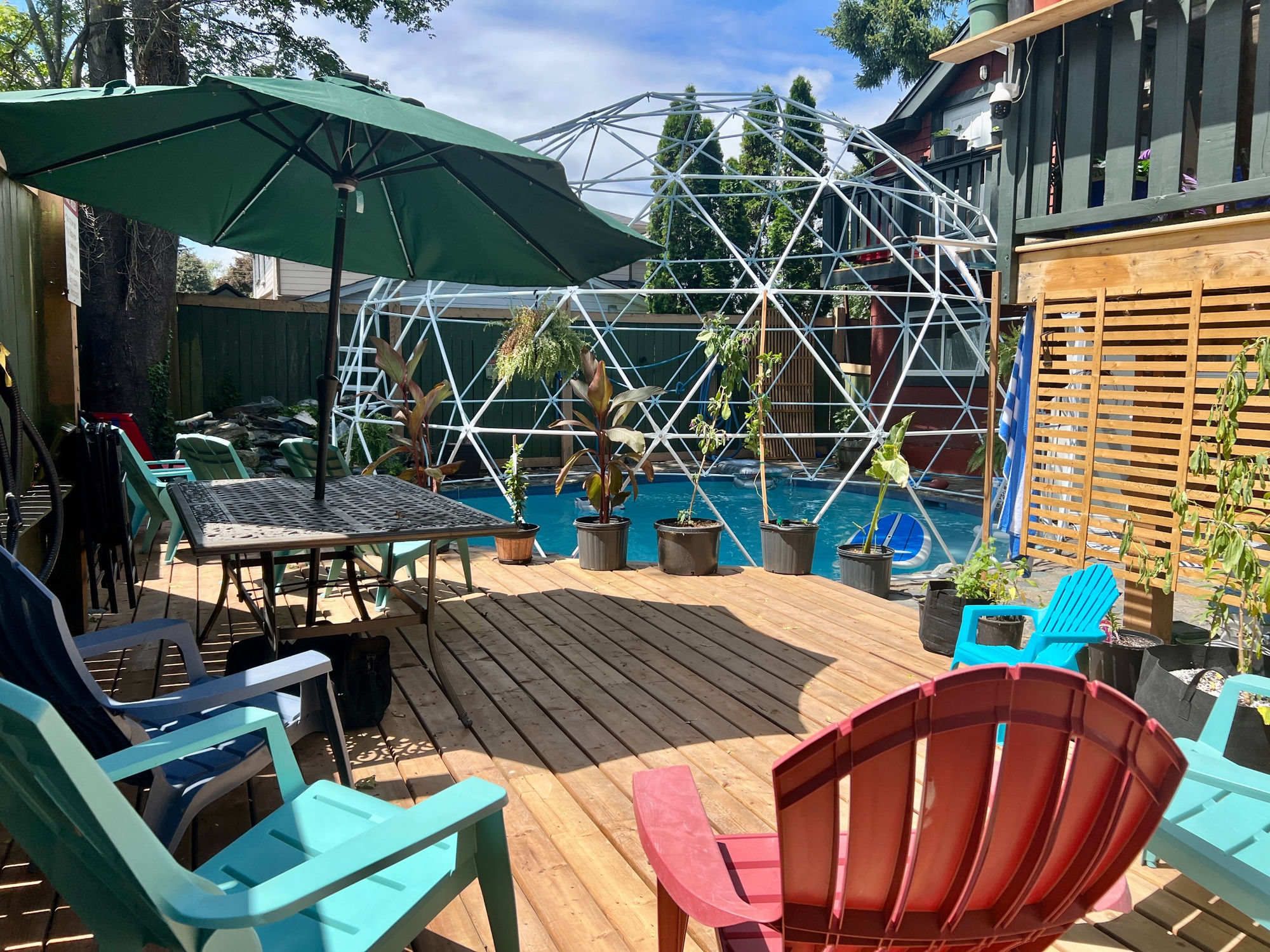 Une terrasse en bois avec des meubles d’extérieur, une piscine et une structure géodésique.