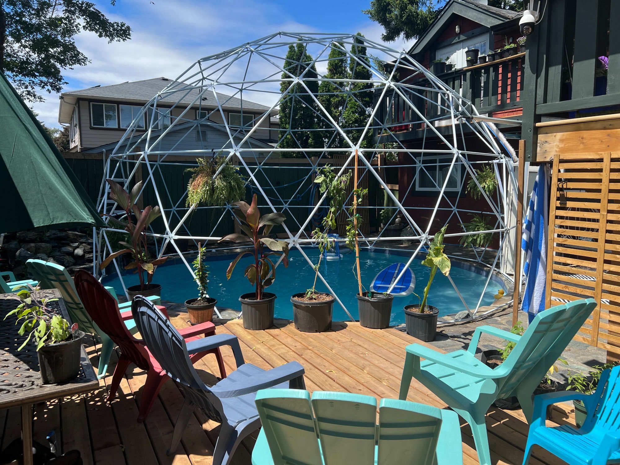 Un'area piscina con una struttura a cupola geodetica, piante in vaso e arredi da esterno.