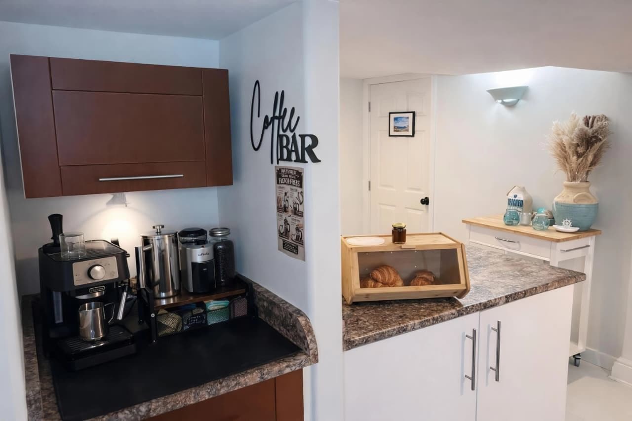 A kitchen with a coffee machine, jars, and a wooden box with croissants.