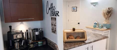 A kitchen with a coffee machine, jars, and a wooden box with croissants.