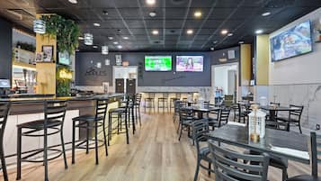 A restaurant with a bar area, multiple seating options, and a television screen displaying a program.