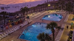 A resort with a pool area, sun loungers, and a view of the beach at sunset. - Sunny Daze 104-Walk-Out Beachfront-Sleeps 6 (Panama City Beach)
