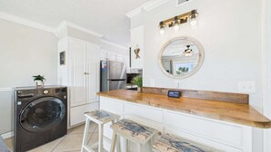 A kitchen with a washing machine, a wooden countertop, and a large mirror. - Sunny Daze 104-Walk-Out Beachfront-Sleeps 6 (Panama City Beach)