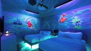 A room with two beds, a nightstand, and a wall with animated characters.