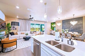 A modern kitchen with a central island, built-in appliances, and a dining area with a view. - New Resort, Private Pool & Spa, Outdoor Theater, Game Room, Minutes to Disney World (Clermont)
