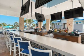 A bar area with a long counter, multiple TVs, and a row of bar stools. - New Resort, Private Pool & Spa, Outdoor Theater, Game Room, Minutes to Disney World (Clermont)