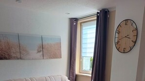 Una sala de estar con un sofá color crema, una mesa de centro de madera y un reloj de pared.