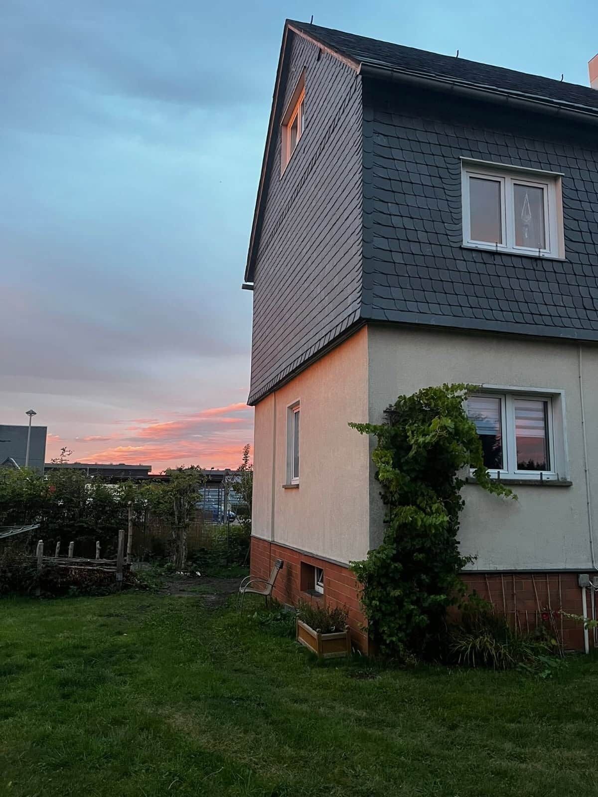Een huis met twee verdiepingen, een schuin dak, een klein raam op de bovenverdieping en een voordeur.
