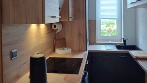Una cocina moderna con armarios de madera, estufa integrada, lavamanos y ventana con vista a follaje.