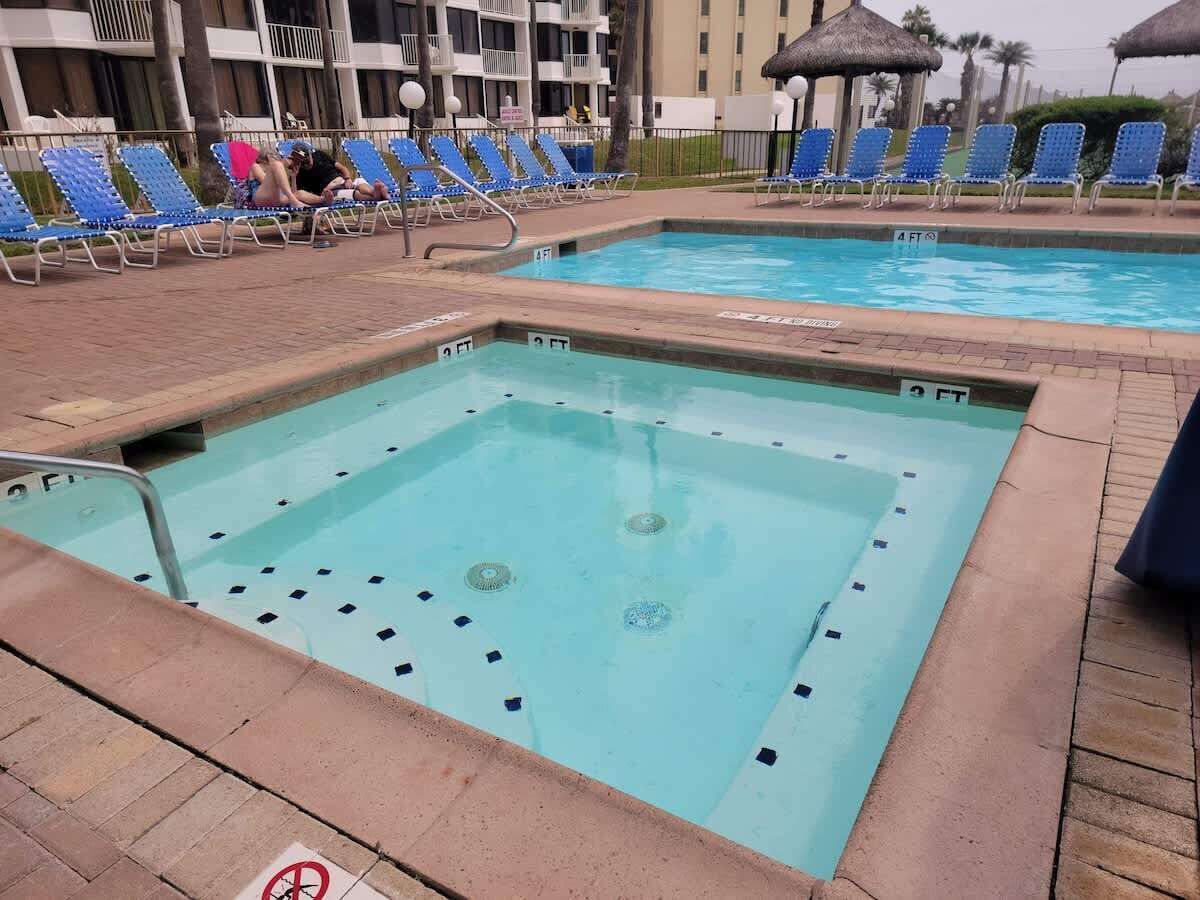 A swimming pool with a diving board and lounge chairs.