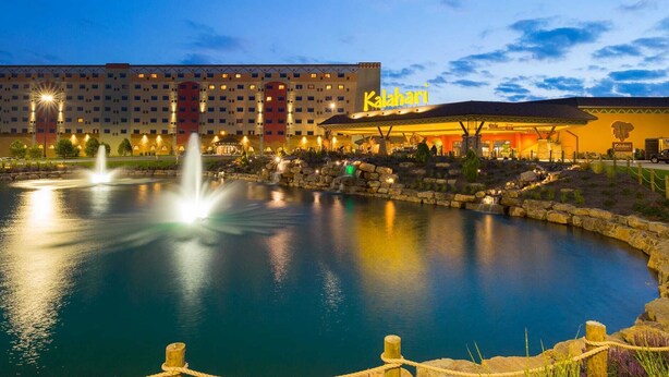 A hotel with a large building, a pool with a fountain, and a sign reading "Kalahari".