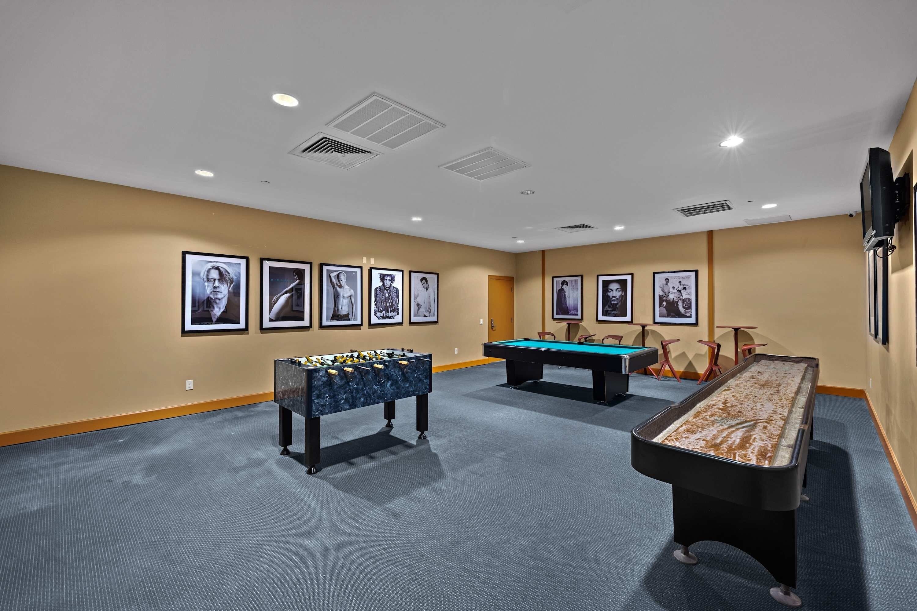 A room with a pool table, foosball table, and billiards table.