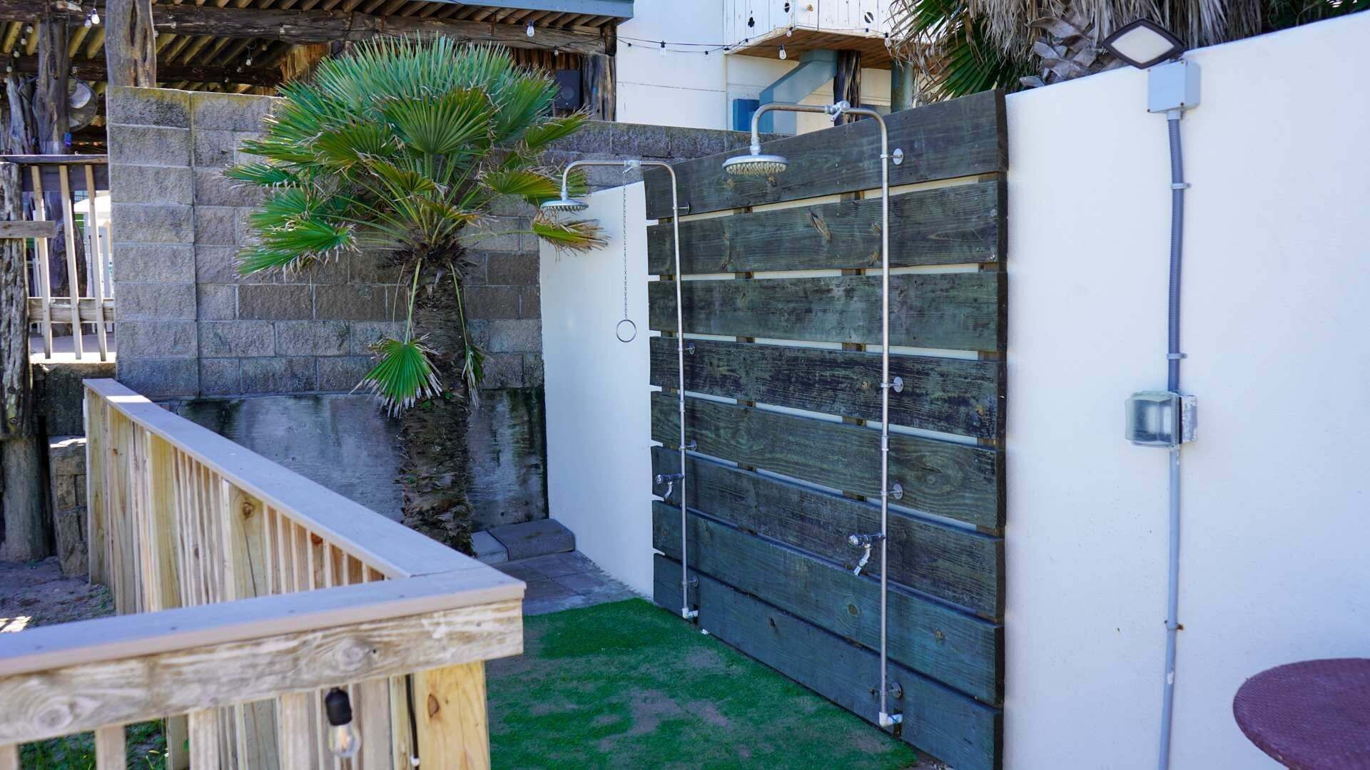 A wooden deck with a stone wall, a palm tree, and a metal gate.