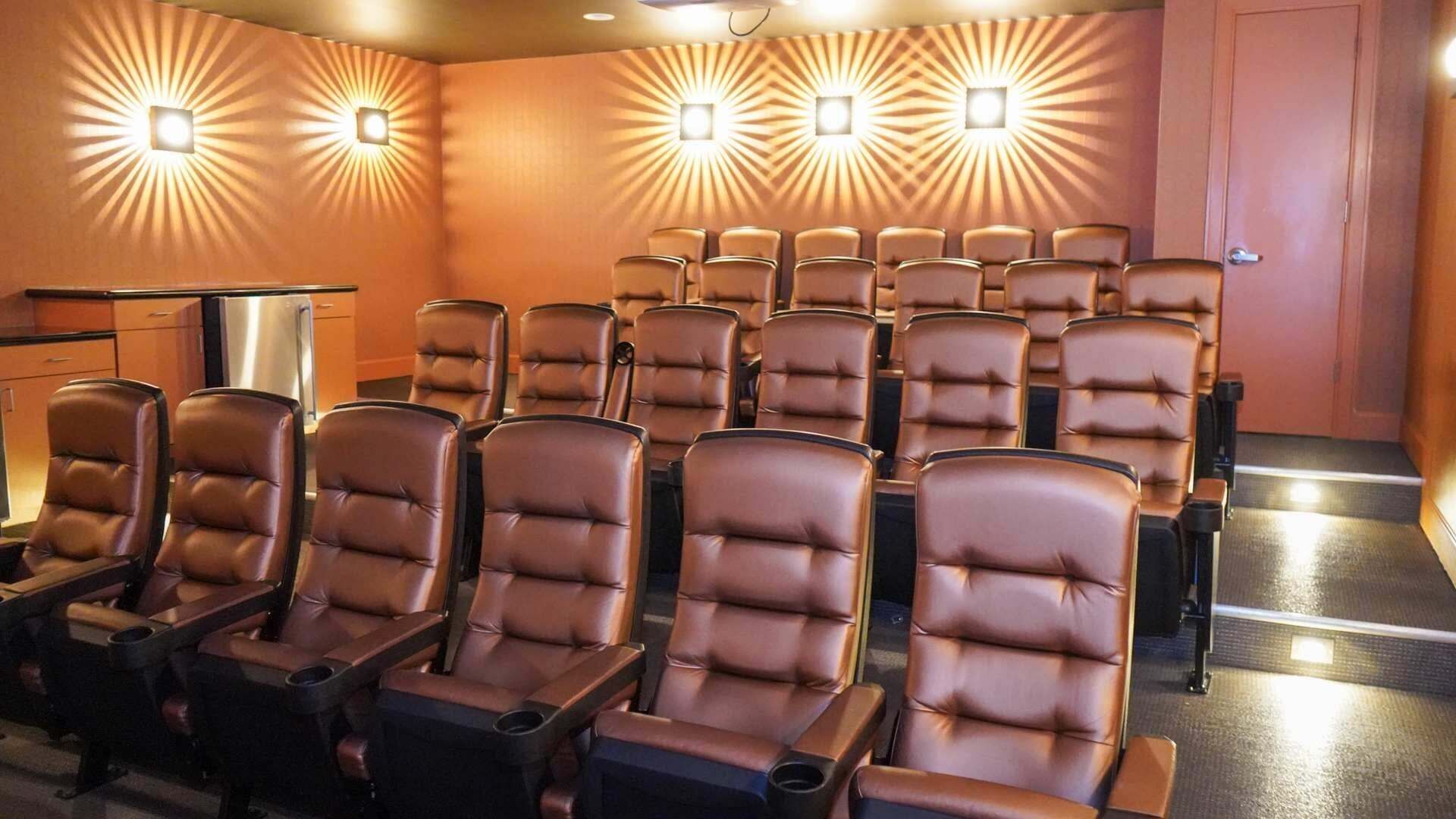 A row of leather recliner chairs with armrests and cup holders, arranged in a theater-style seating layout.