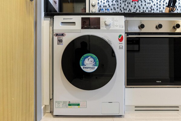 Un appareil combiné lave-linge et sèche-linge de la marque Westpoint, à chargement frontal, doté d’un écran numérique, d’un panneau de commande et d’un verrou de sécurité rouge.