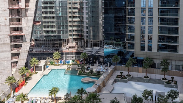 A high-rise building with a swimming pool, palm trees, and a mural. - Lux BnB Aykon Tower (Dubai)