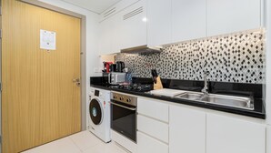 A modern kitchen with white cabinets, a stainless steel sink, a built-in oven, a microwave, and a coffee maker. - Lux BnB Aykon Tower (Dubai)