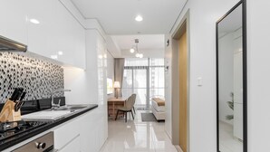 A modern kitchen with a stove, sink, and dining area. - Lux BnB Aykon Tower (Dubai)