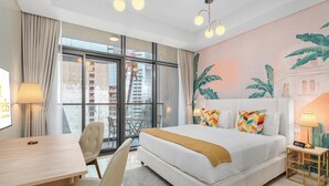 A hotel room with a large bed, a desk, and a view of the city through large windows. - Lux BnB Aykon Tower (Dubai)