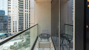 A balcony with two chairs and a table, overlooking a cityscape with tall buildings. - Lux BnB Aykon Tower (Dubai)