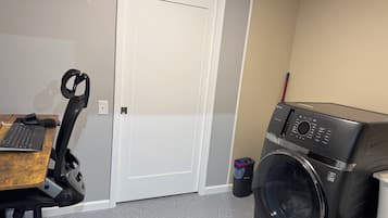 Une buanderie équipée d’un lave-linge, d’une porte et d’un bureau avec un clavier et une souris.