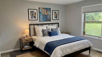 A bedroom with a bed, bedside tables, a window, and artwork on the wall.